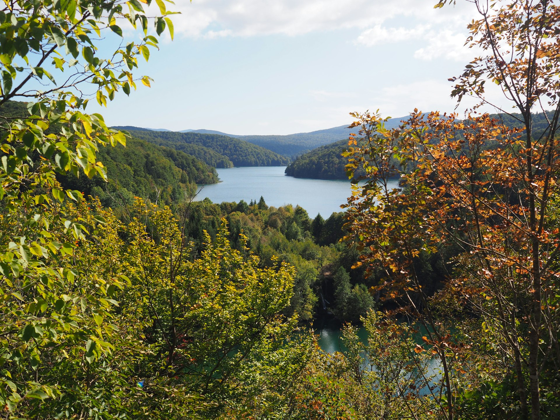 Green trees on mountain near body of water at Plitvice Lakes in early autumn