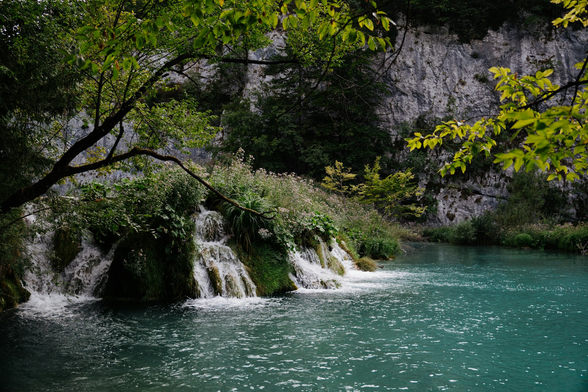 Serene waterfall cascading into clear turquoise lake at Plitvice Lakes in spring
