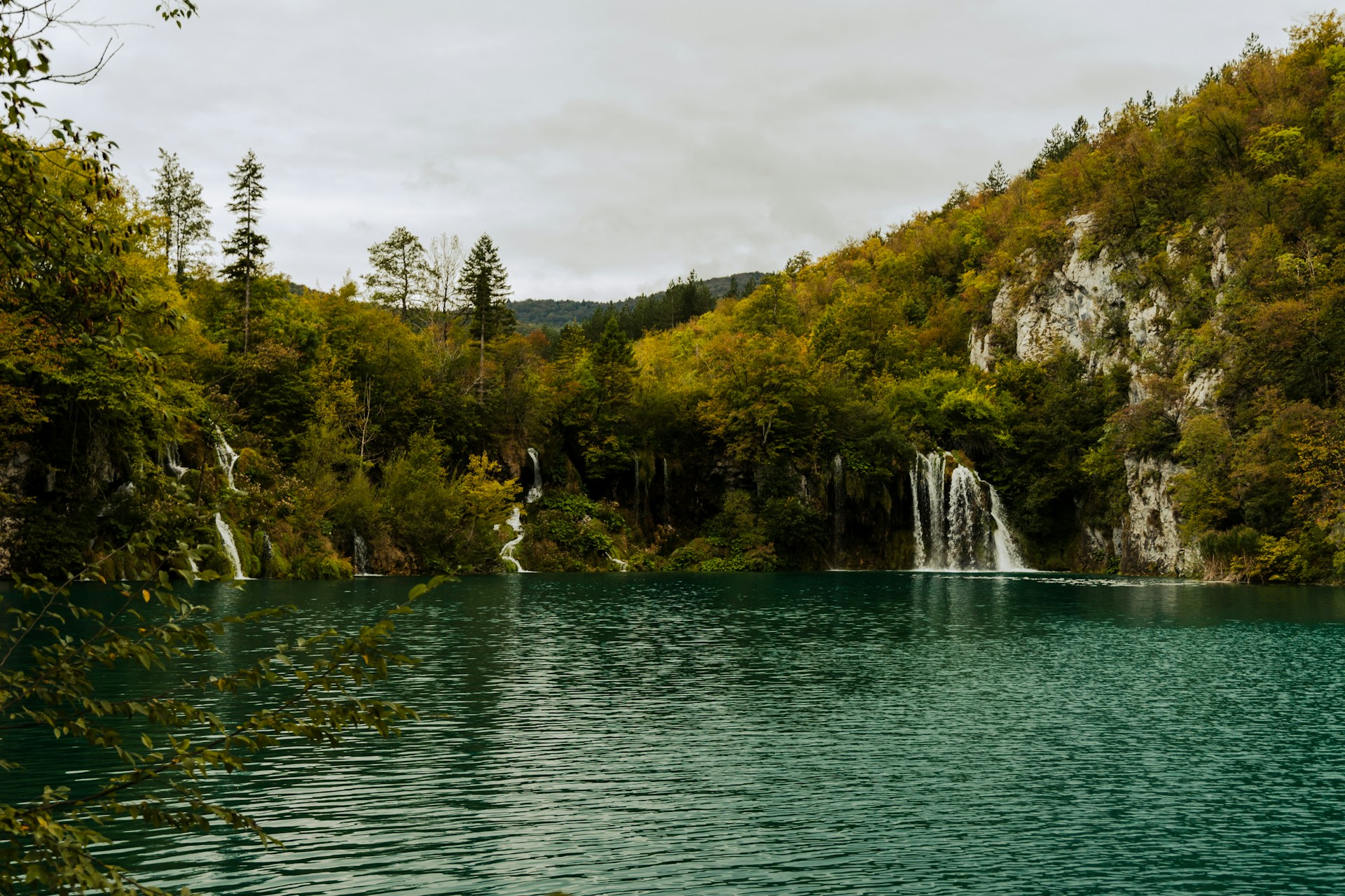 Crystal clear turquoise lake surrounded by snow-covered trees at Plitvice Lakes in winter