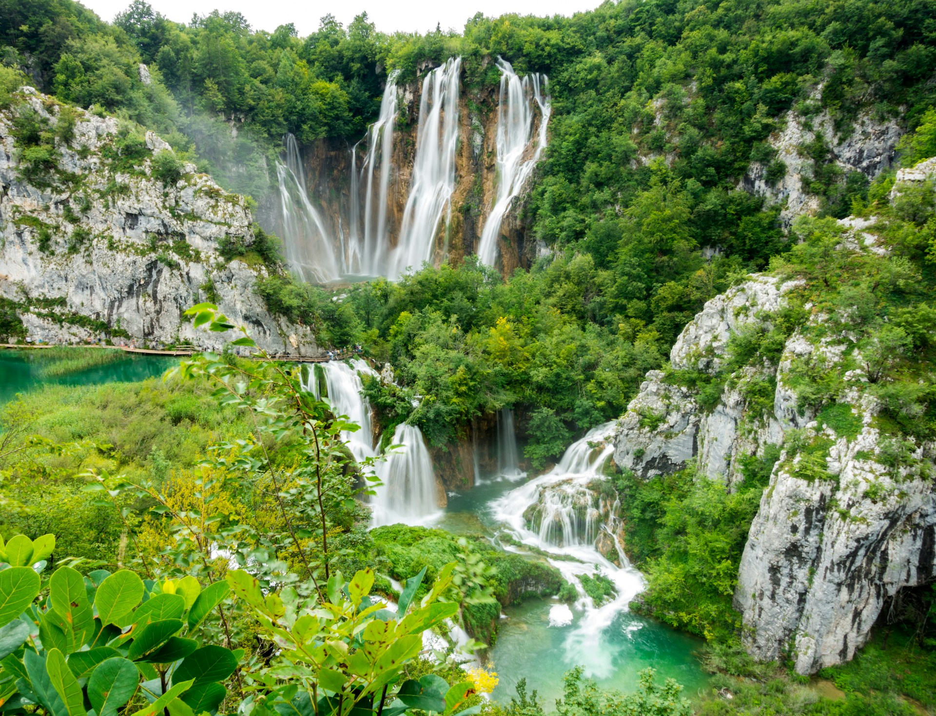 Multi-tiered waterfalls cascading through lush forest at Plitvice Lakes